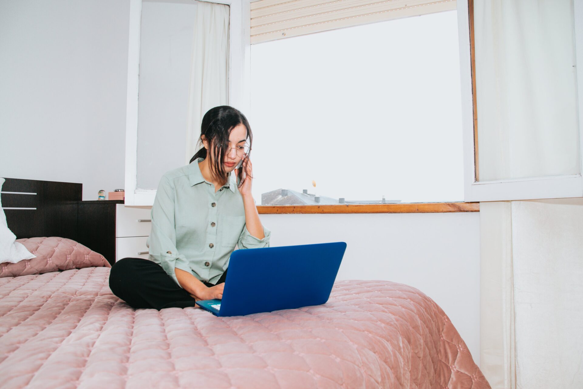 自宅で電話をしながらノートPCで仕事を行うビジネスパーソン
